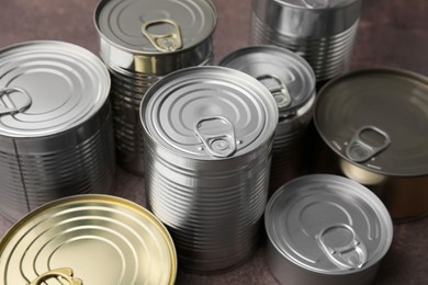 Photo of Many closed tin cans on brown table, closeup