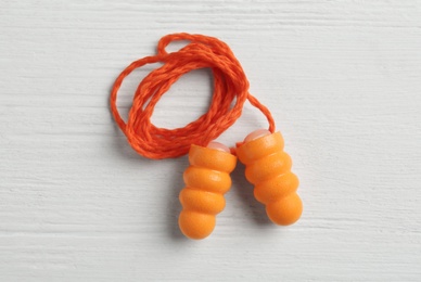 Photo of Pair of orange ear plugs with cord on white wooden background, top view