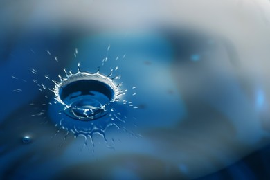 Splash of clear water with drops on blue background, closeup. Space for text