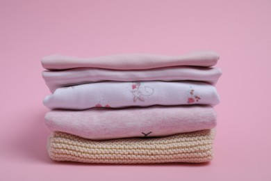 Photo of Stack of clean baby clothes on pink background