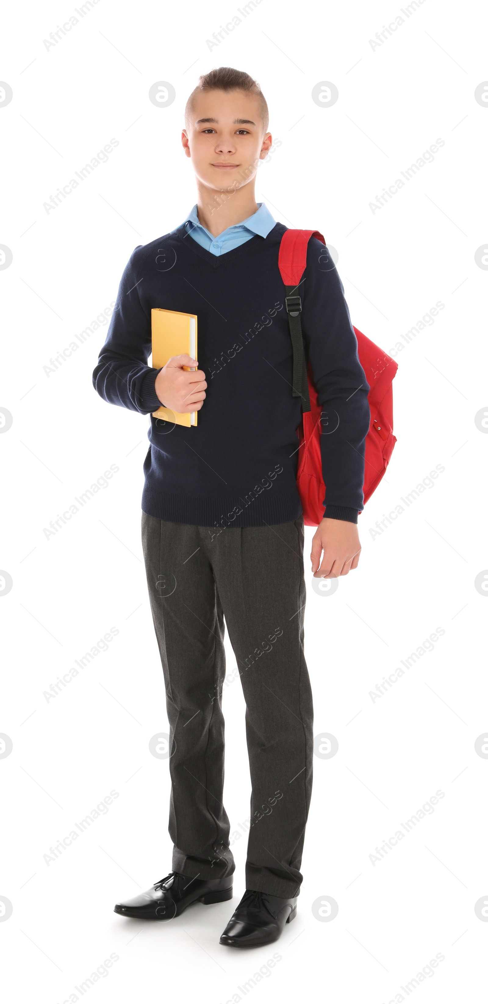 Photo of Full length portrait of teenage boy in school uniform with backpack and book on white background
