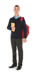 Full length portrait of teenage boy in school uniform with backpack and book on white background