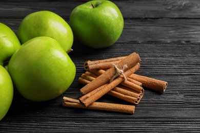 Photo of Fresh apples and cinnamon sticks on wooden table