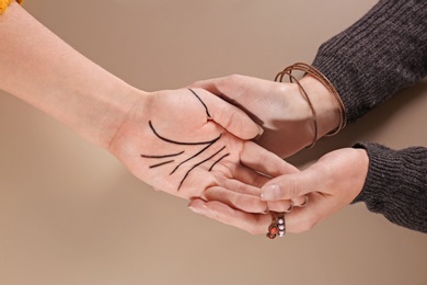 Chiromancer reading lines on woman's palm against color background, top view