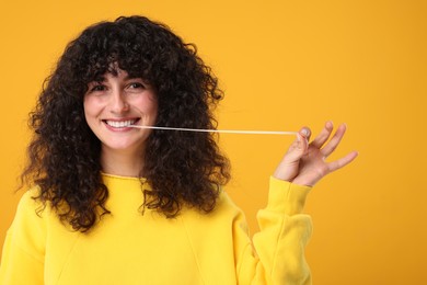 Photo of Happy young woman stretching bubble gum on orange background