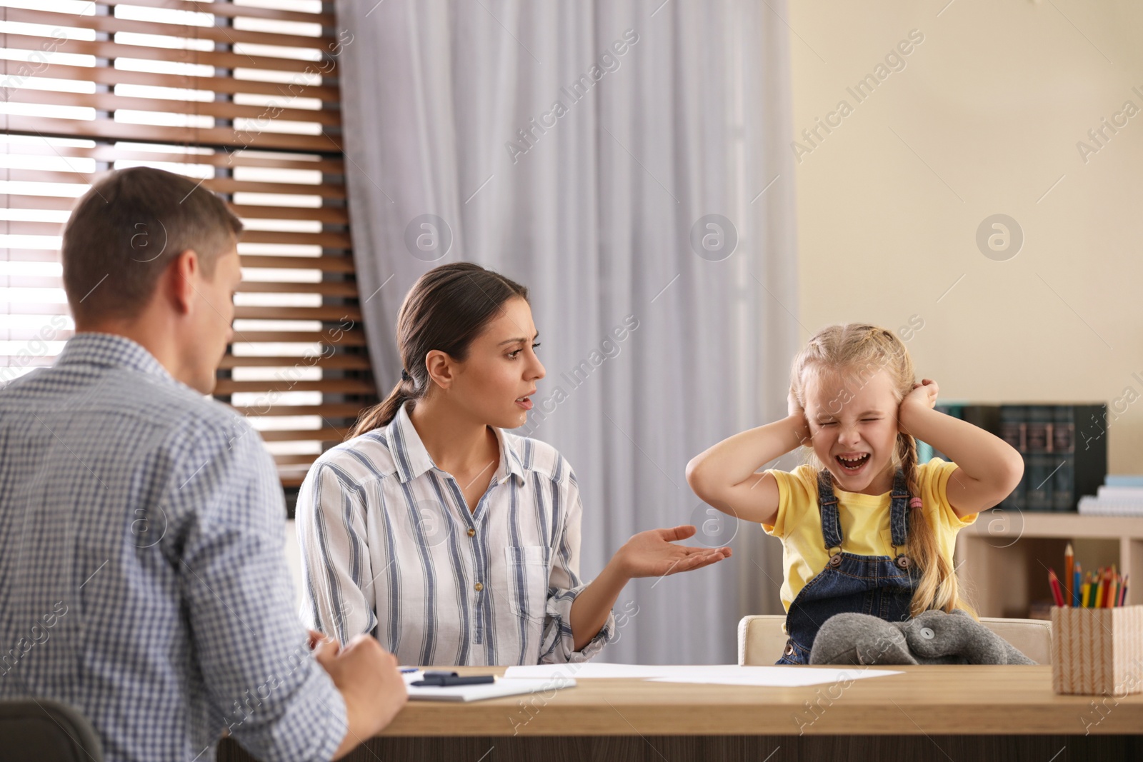 Photo of Child psychotherapist working with little girl and her mother in office