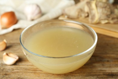 Photo of Glass bowl with delicious bone broth on wooden table