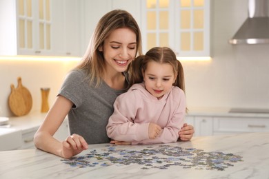 Photo of Woman and his little daughter playing with puzzles at home