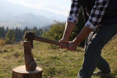 Photo of Man with axe cutting firewood on hill, closeup