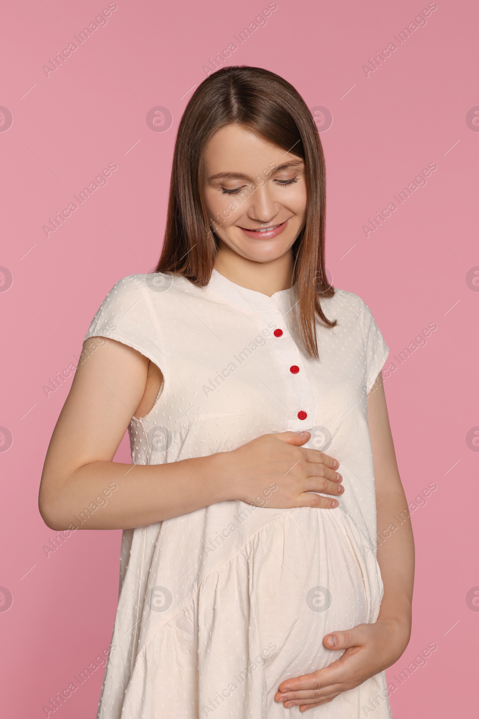 Photo of Happy young pregnant woman on pink background