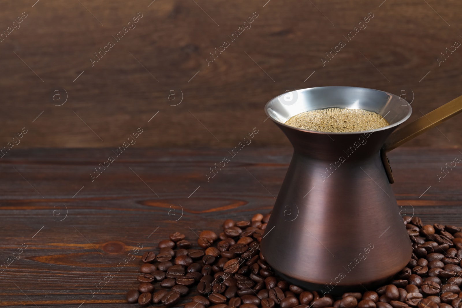 Photo of Hot turkish coffee pot and beans on wooden table, space for text