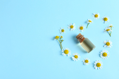 Photo of Flat lay composition with chamomile essential oil on light blue background. Space for text
