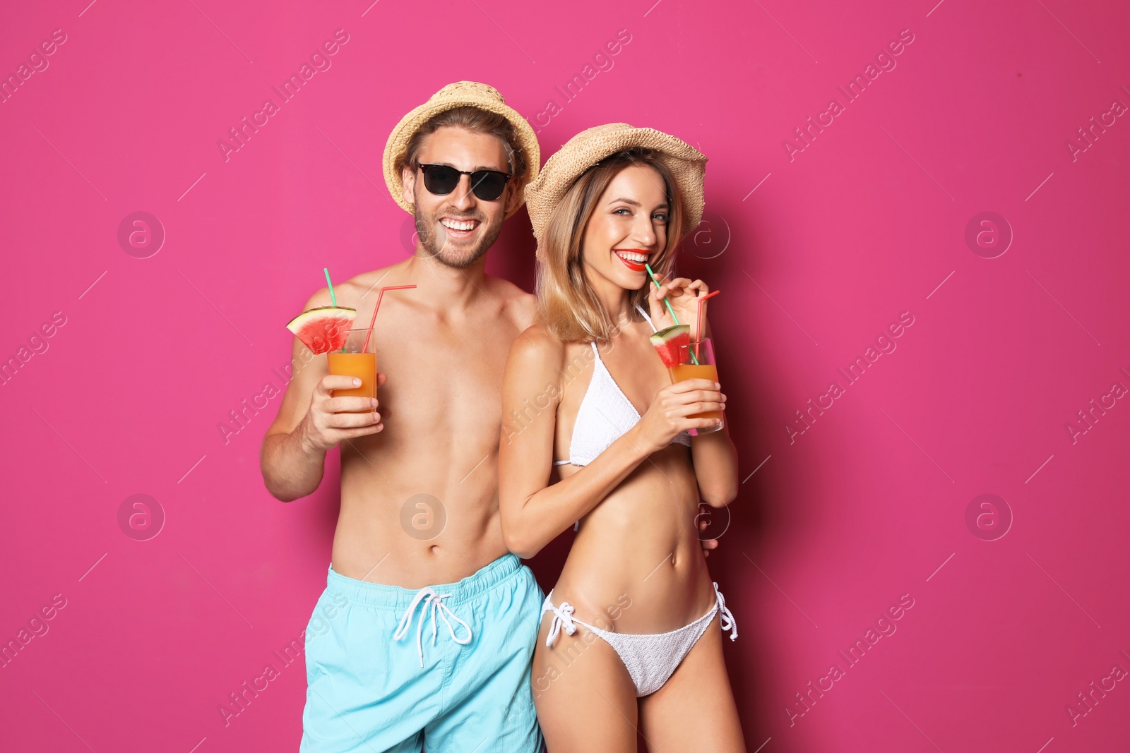 Photo of Happy young couple in beachwear with cocktails on color background