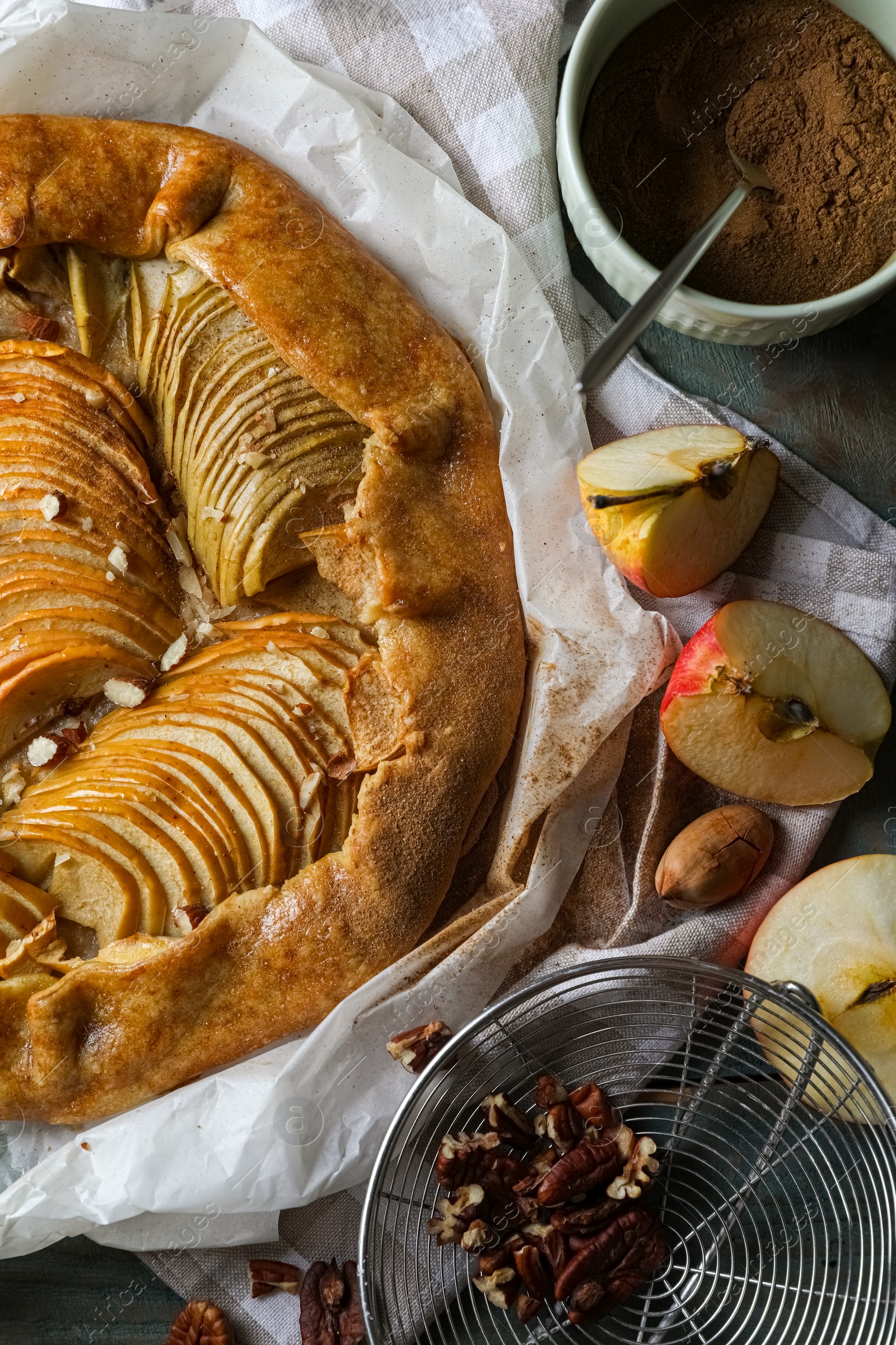 Photo of Delicious apple galette with pecans and cinnamon on wooden table, flat lay