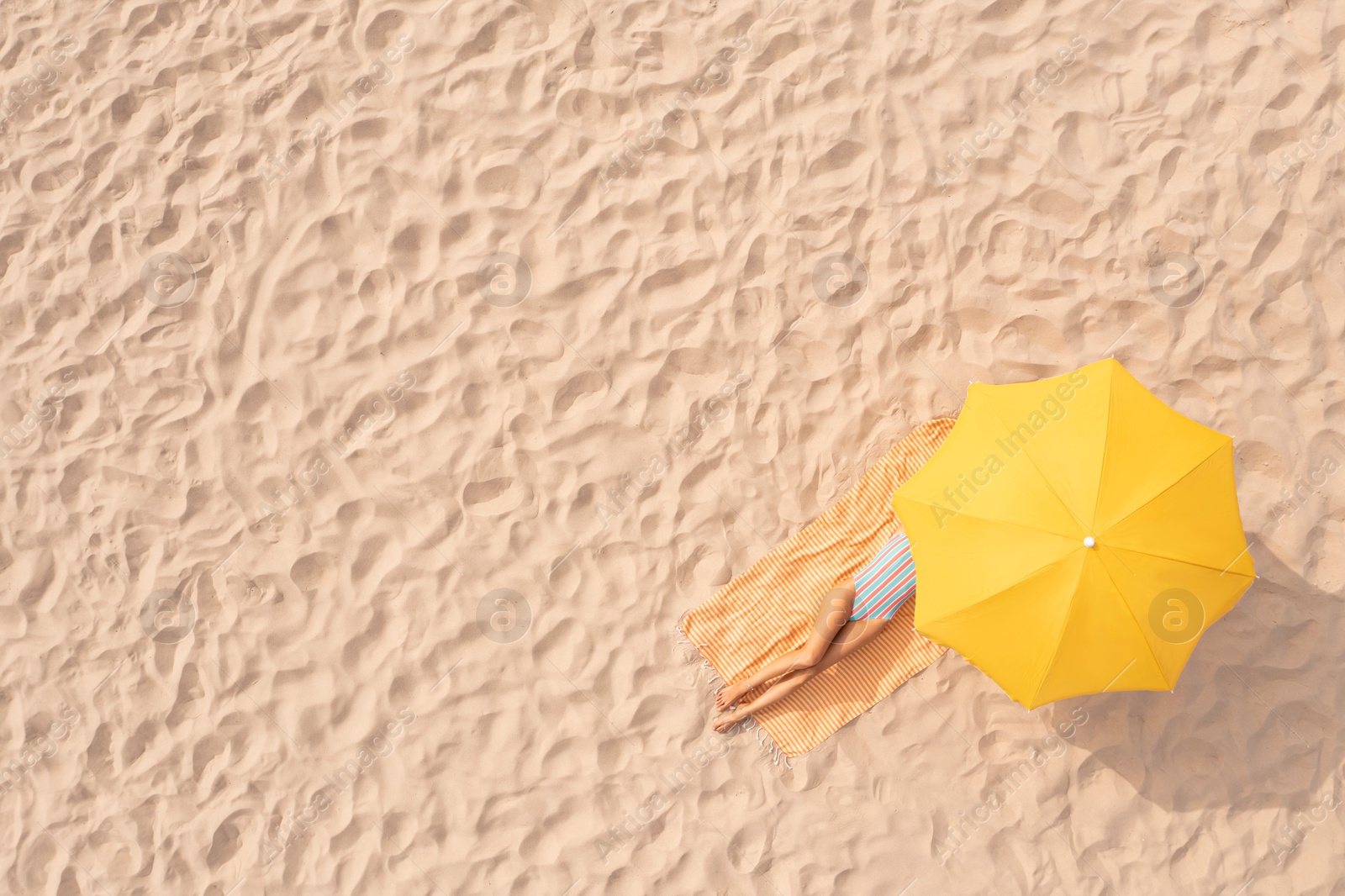 Image of Woman resting under yellow beach umbrella at sandy coast, aerial view. Space for text