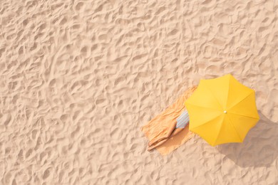 Image of Woman resting under yellow beach umbrella at sandy coast, aerial view. Space for text