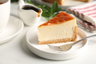 Piece of delicious caramel cheesecake served on white marble table, closeup