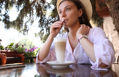 Photo of Beautiful young woman with coffee at table in outdoor cafe