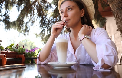 Beautiful young woman with coffee at table in outdoor cafe