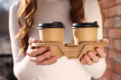 Woman holding paper coffee cups outdoors, closeup