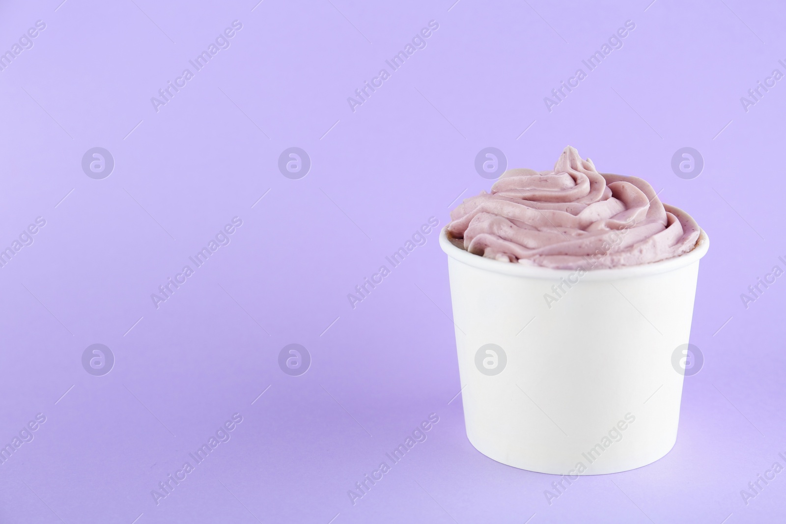 Photo of Cup with tasty frozen yogurt on violet background. Space for text