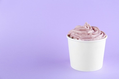 Cup with tasty frozen yogurt on violet background. Space for text