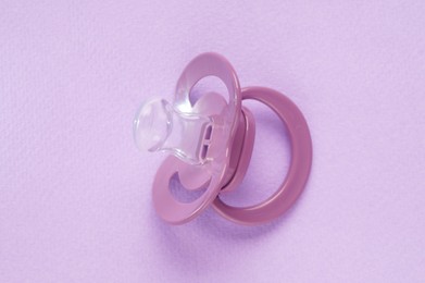 Photo of One new baby pacifier on pink background, top view