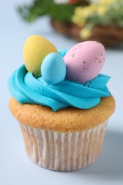 Photo of Tasty decorated Easter cupcake on light blue background, closeup