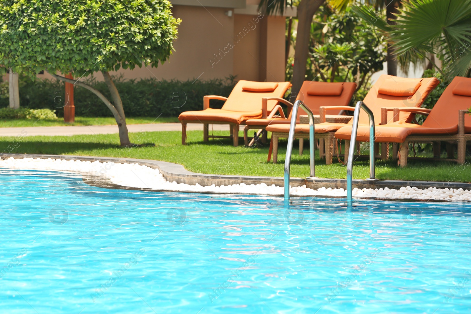 Photo of Sunbeds near modern swimming pool at resort