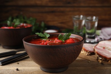 Stylish brown clay bowl with Ukrainian borsch served on wooden table