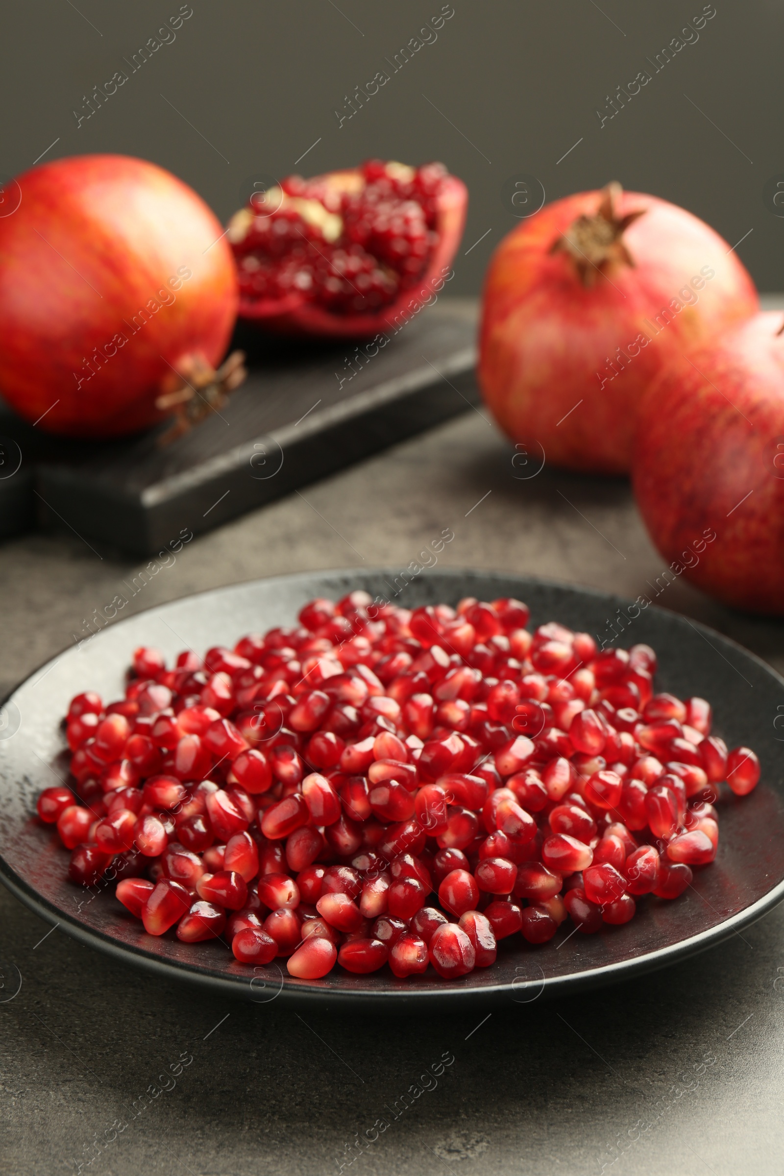 Photo of Ripe juicy pomegranate grains on grey table