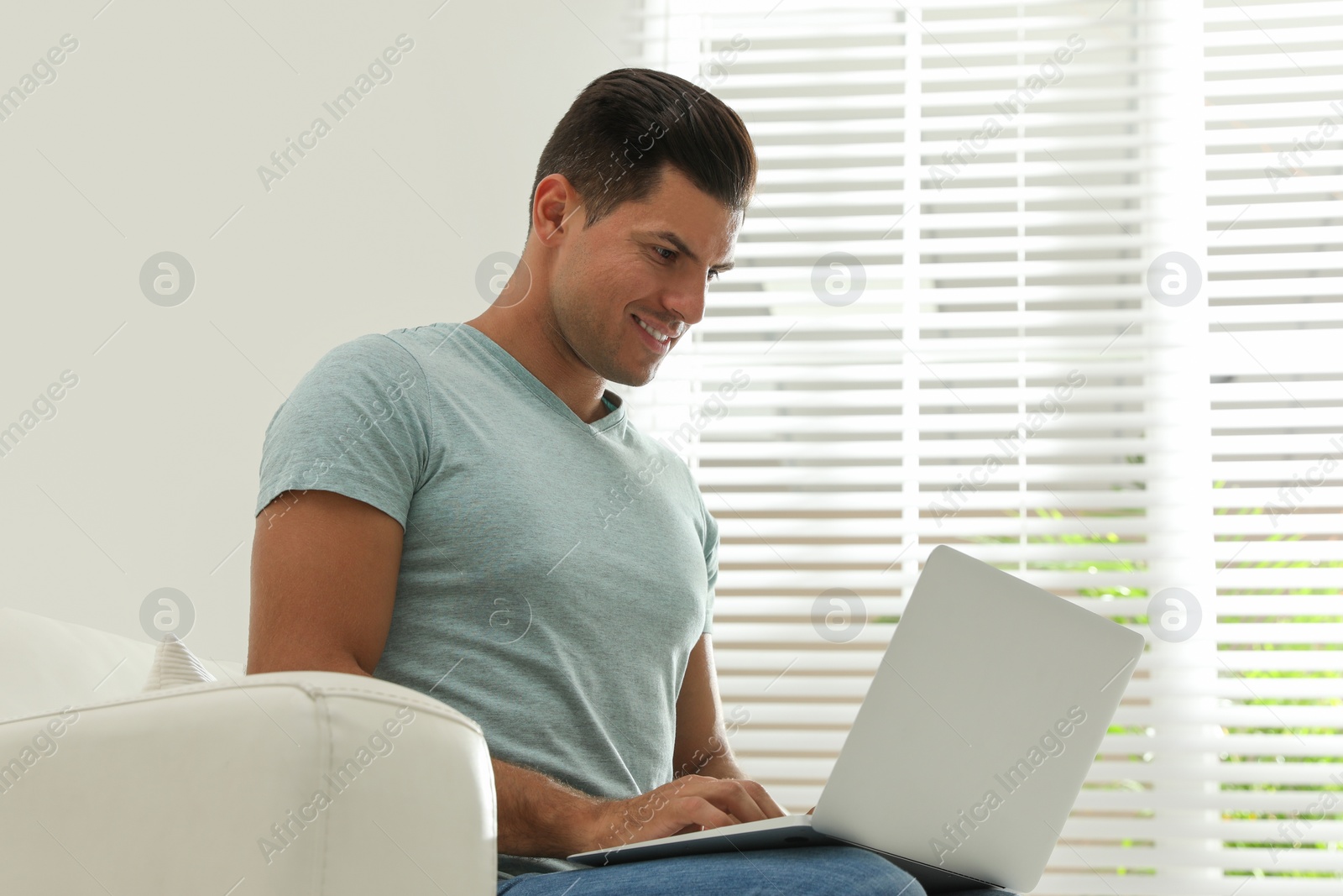 Photo of Man using laptop for search on sofa at home