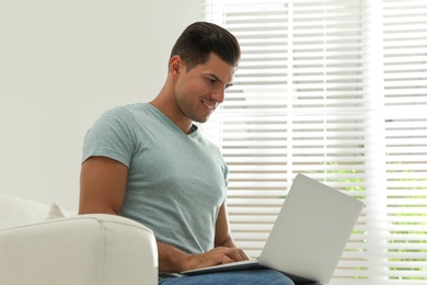 Photo of Man using laptop for search on sofa at home