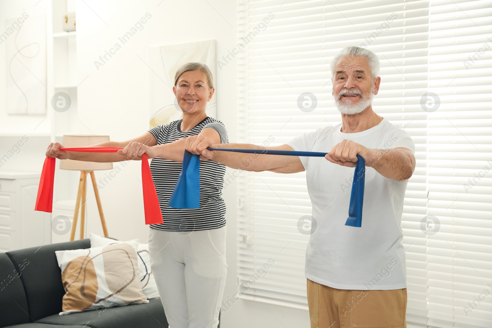 Photo of Senior couple doing exercise with fitness elastic bands at home