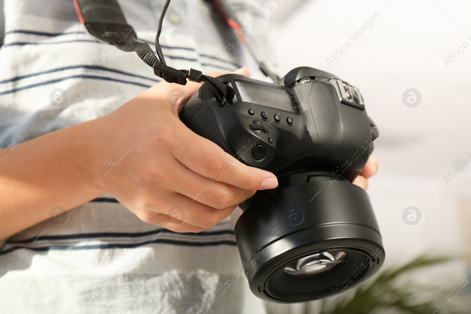 Photo of Female photographer with professional camera on blurred background, closeup