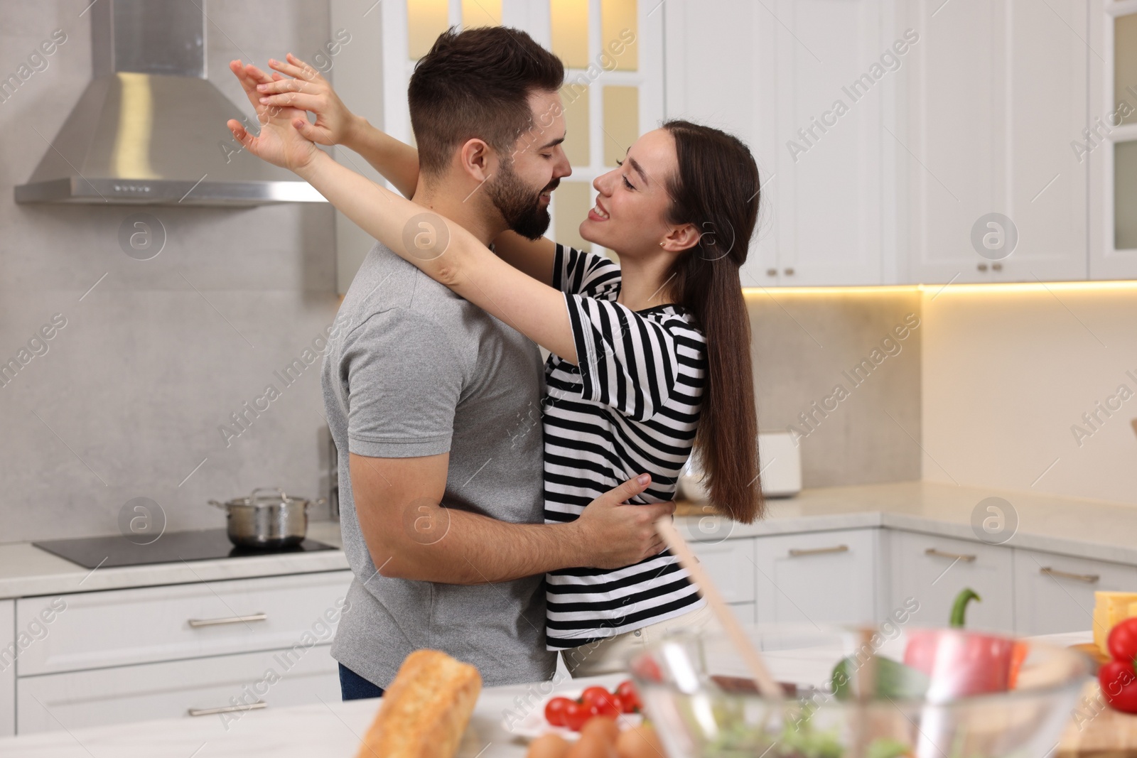 Photo of Happy lovely couple dancing together while cooking in kitchen