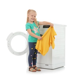 Cute little girl with laundry near washing machine on white background