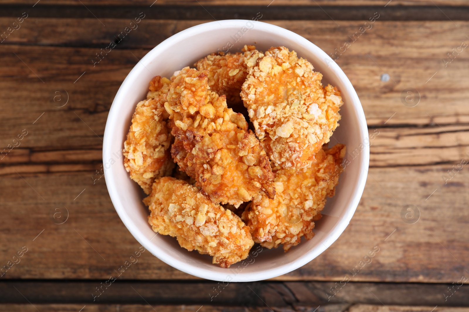 Photo of Bucket with yummy nuggets on wooden table, top view