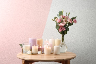 Composition with burning candles on table against color background