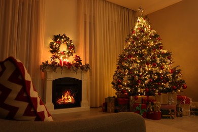 Photo of Beautiful Christmas tree and gifts near fireplace in festively decorated living room