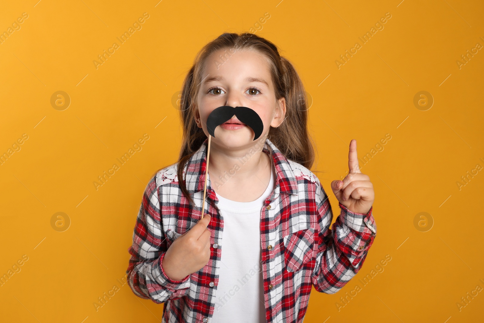 Photo of Funny little girl with fake mustache on yellow background