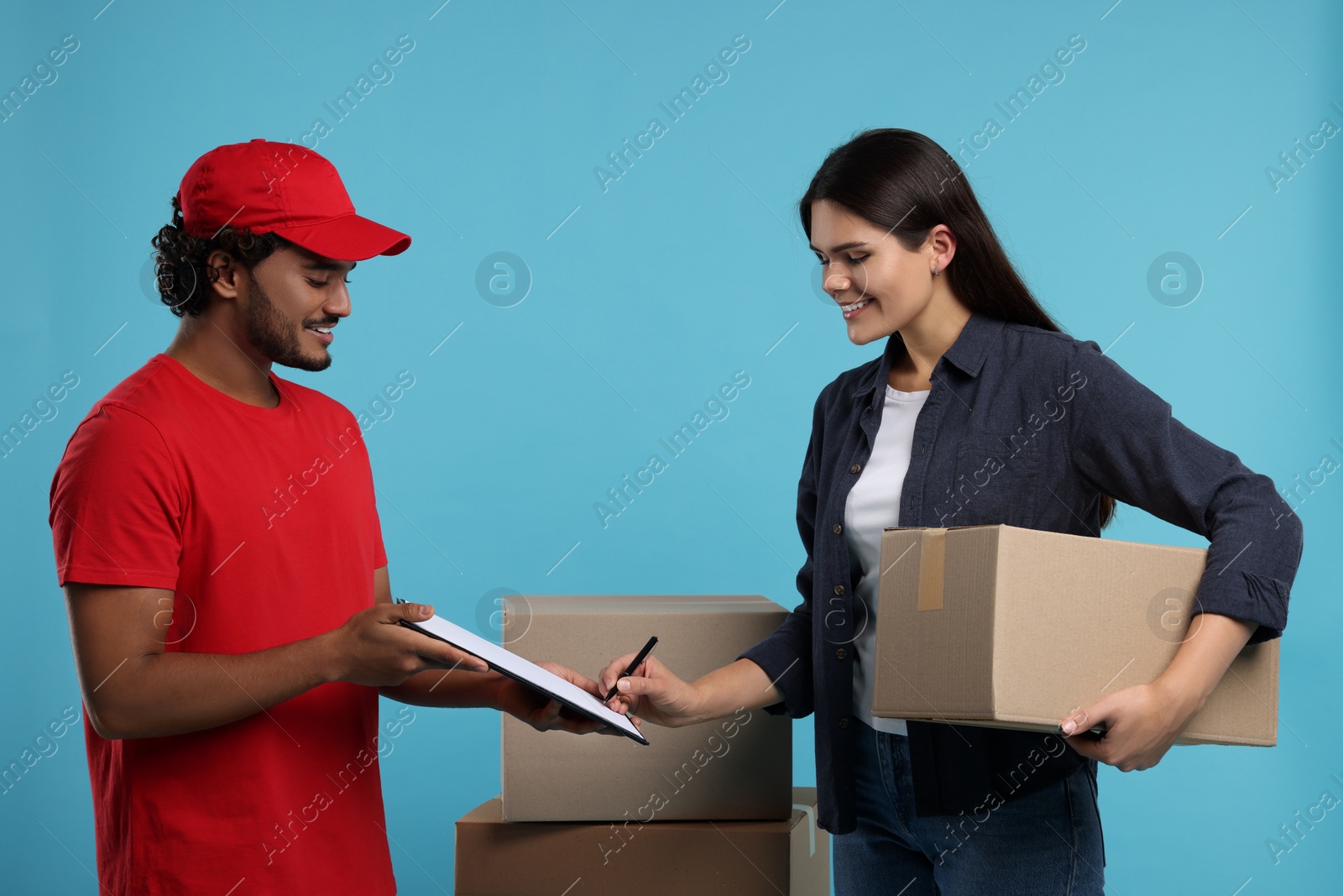 Photo of Smiling woman signing order receipt on light blue background. Courier delivery