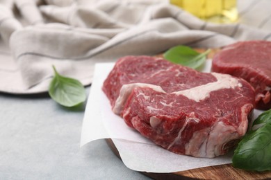 Photo of Fresh raw cut beef and basil leaves on grey table, closeup. Space for text