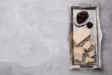 Pieces of tasty halva and dates served in vintage tea set on light grey table, top view. Space for text