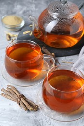 Photo of Aromatic licorice tea and dried sticks of licorice root on light gray textured table