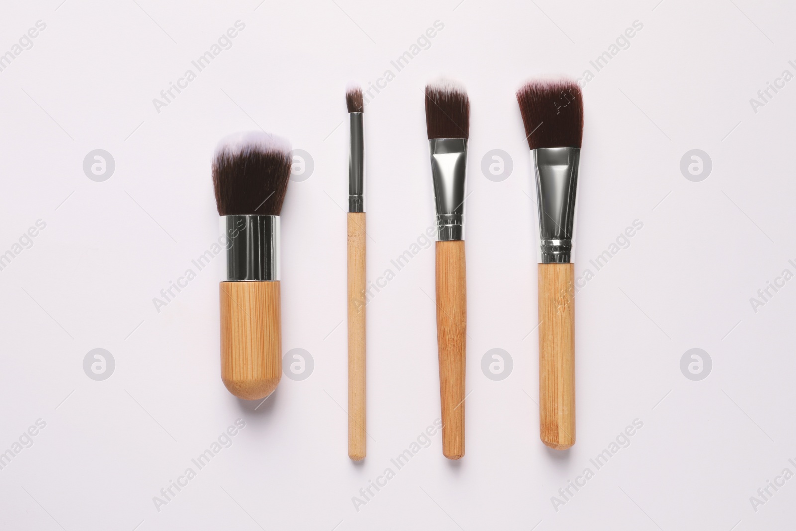 Photo of Different makeup brushes on white background, flat lay