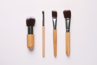 Different makeup brushes on white background, flat lay