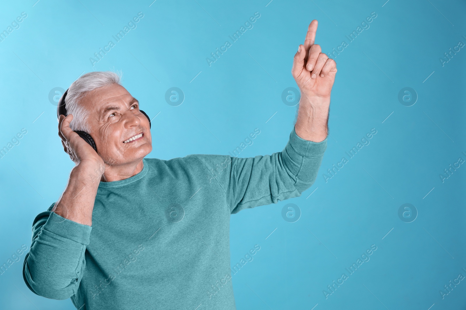 Photo of Mature man enjoying music in headphones on color background