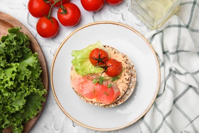 Photo of Crunchy buckwheat cakes with salmon, tomatoes and greens on white table, flat lay