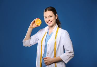 Photo of Nutritionist with ripe orange on blue background